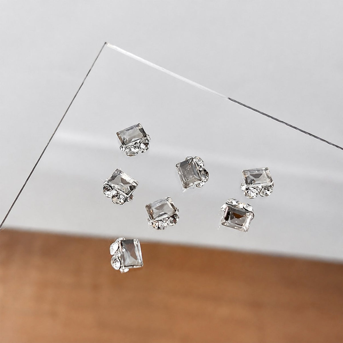 Clear rectangular crystal nail charms on a display card
