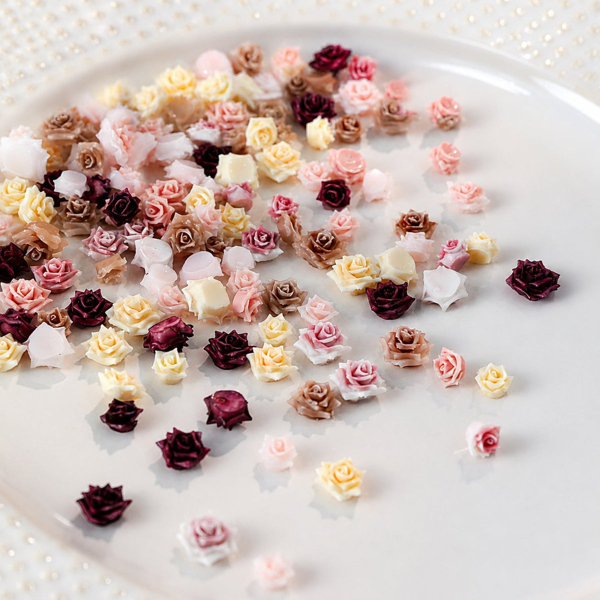 Mixed pastel 3D rose nail-art charms on a white surface