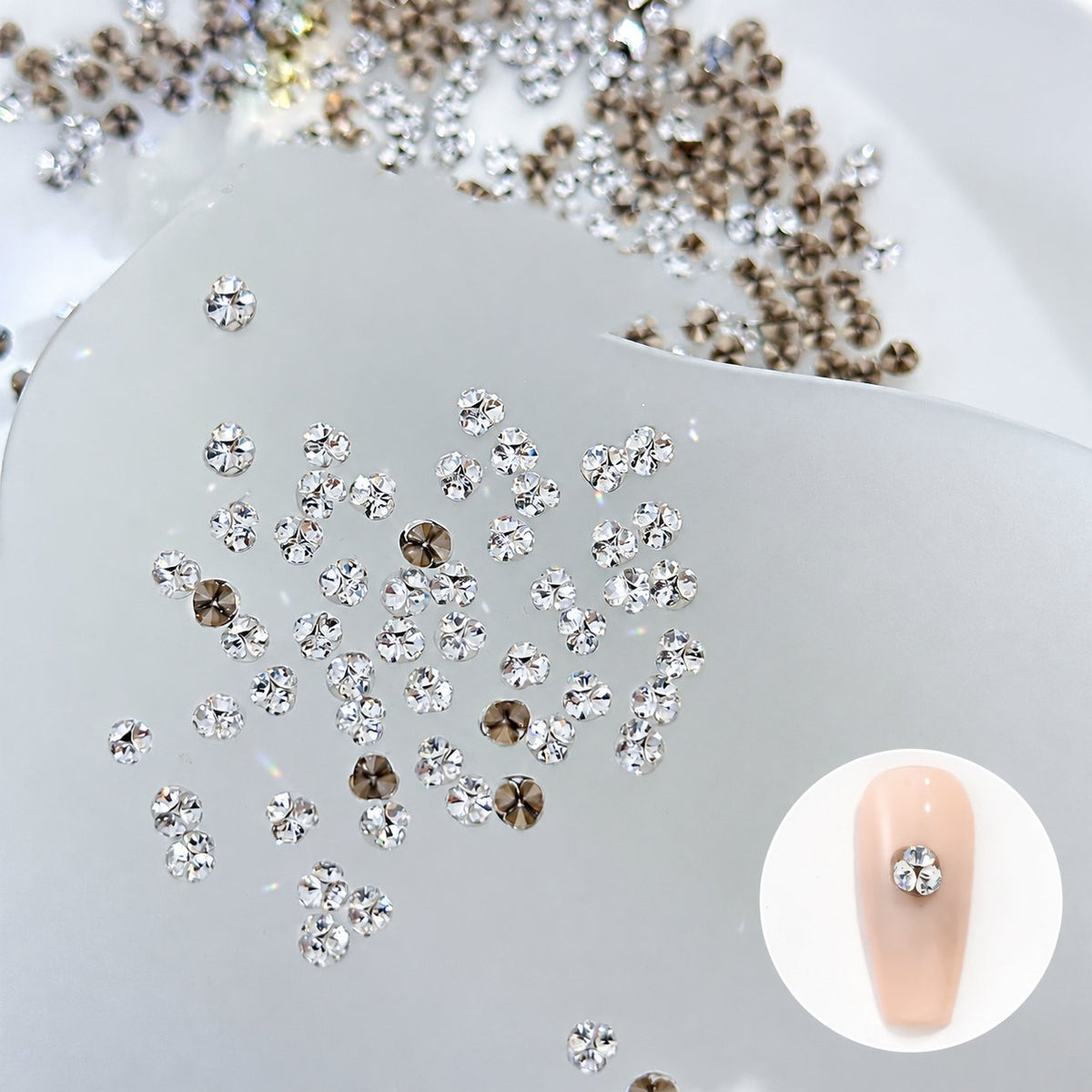 Silver faceted nail rhinestones shown on a nude nail swatch