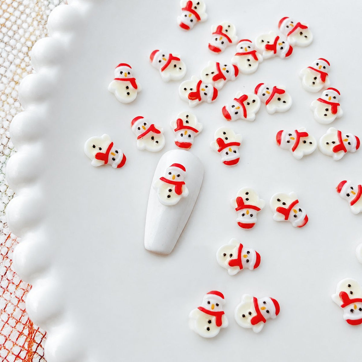 White and red Christmas snowman nail charms on a sample nail tip