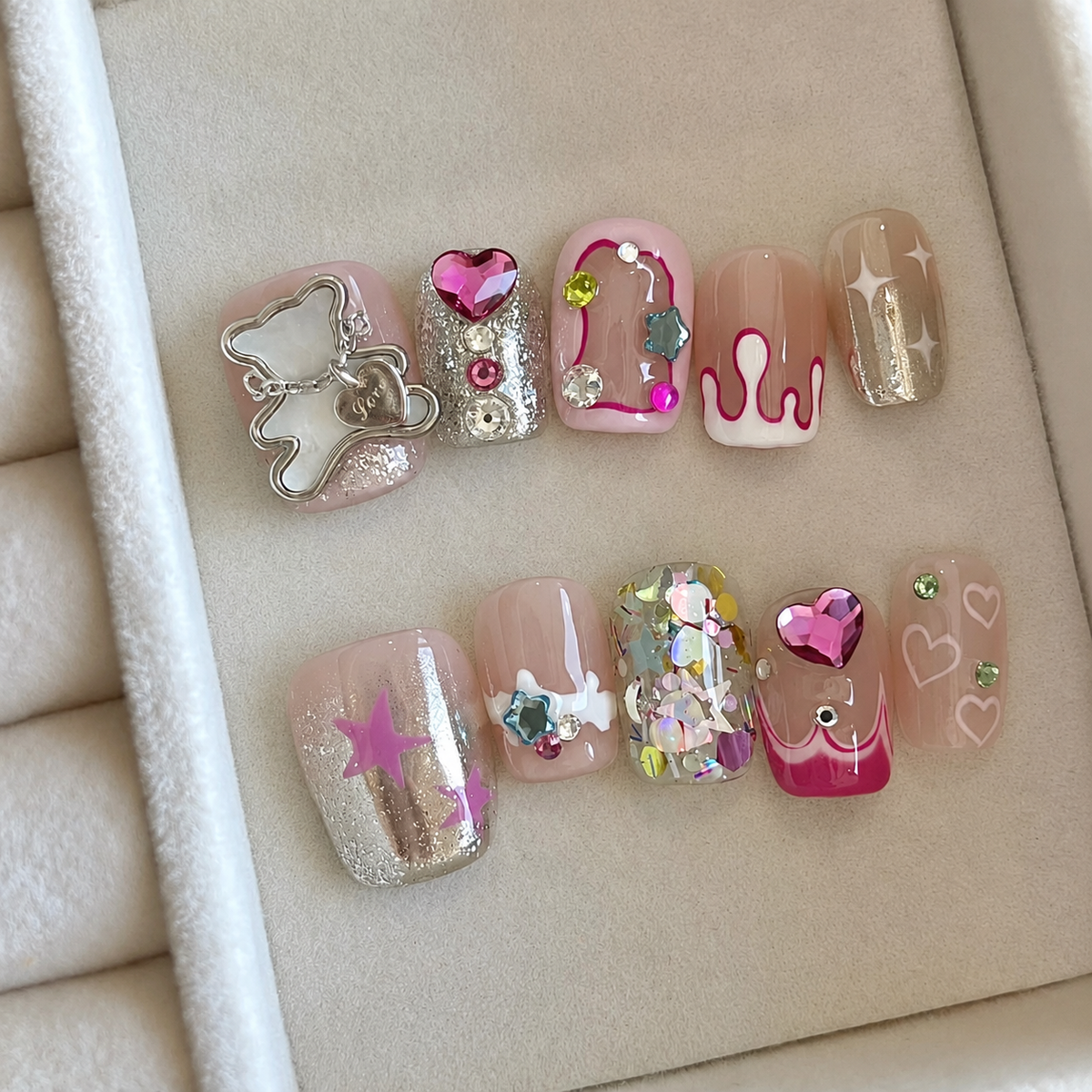 Glitter nail art sample tips with rhinestones, hearts, stars, and pink designs