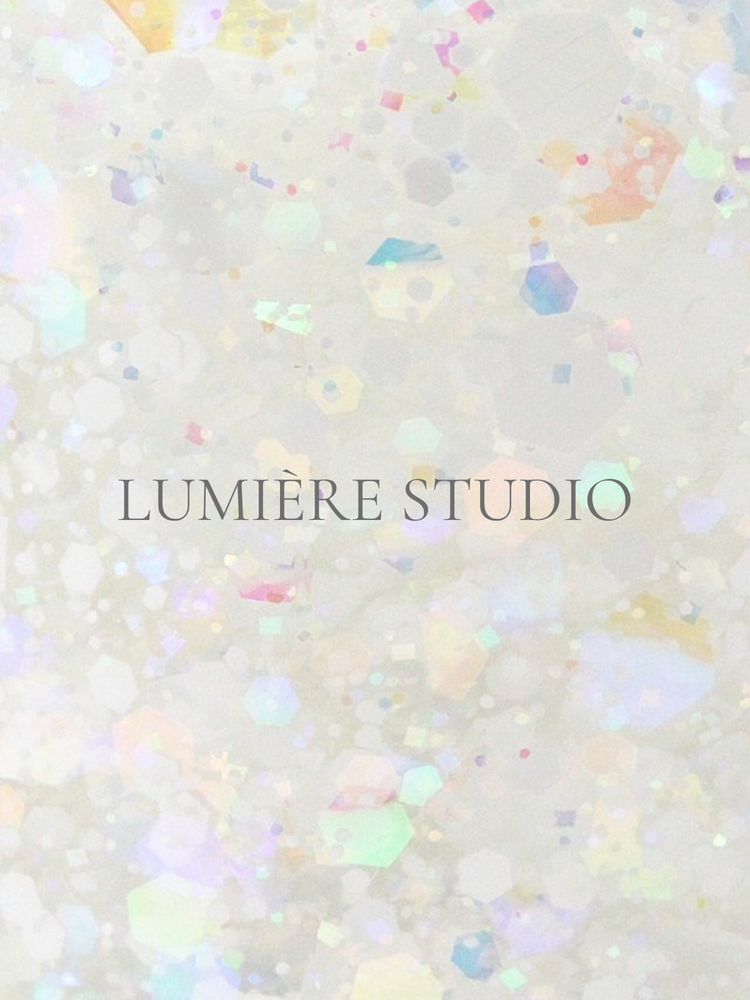 A warm beige still-life photograph featuring chrome, opal, and glitter nail powders with gold and silver leaf flakes in small jars, softly lit in a professional studio setting.