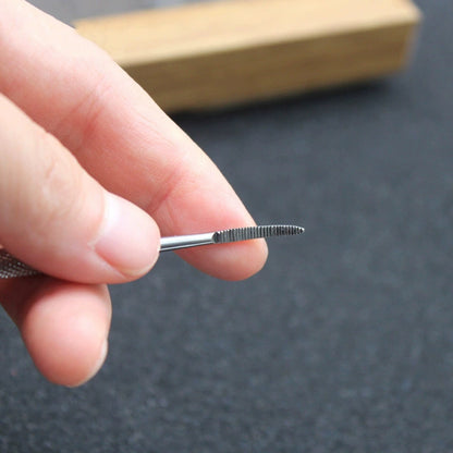 Curved nail file tip held between fingers for scale