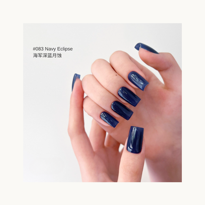 Smoky deep blue press-on nails in shade 084, shown on hands with a soft light background.
