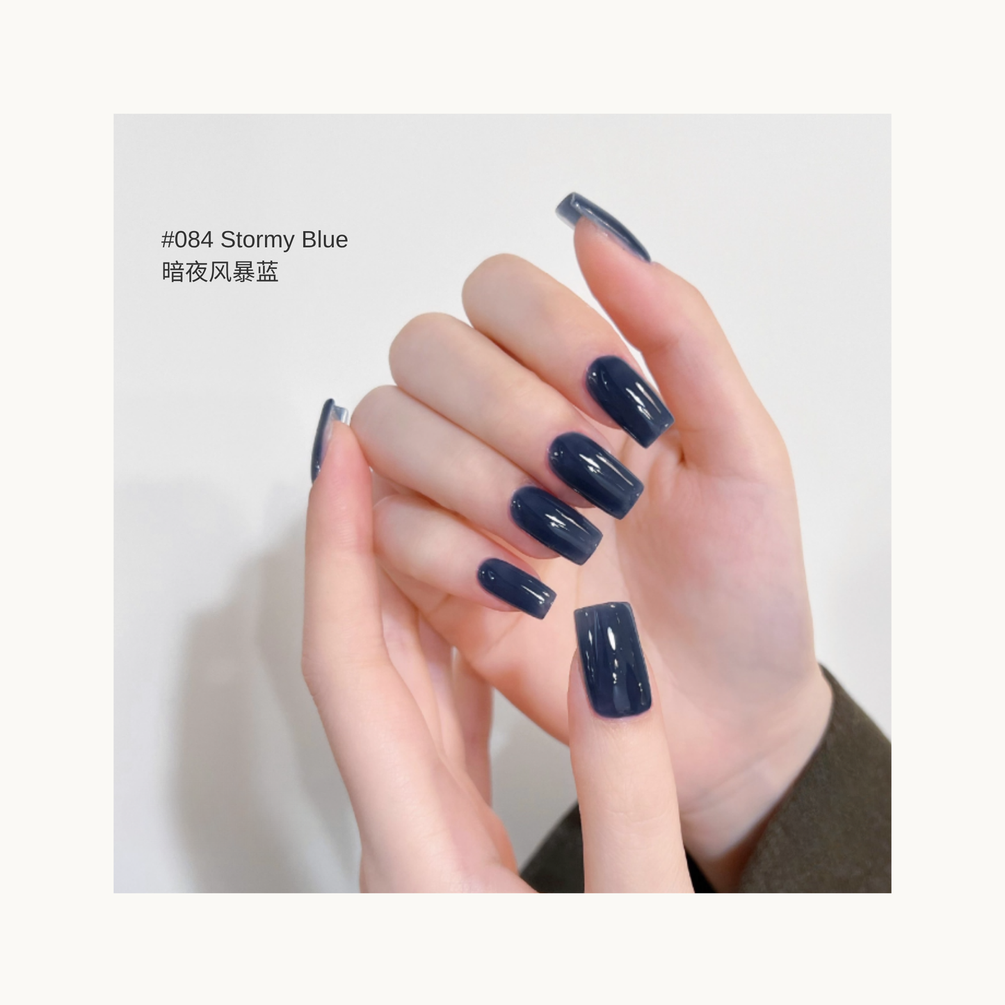 Smoky deep blue press-on nails in shade 084, shown on hands with a soft light background.
