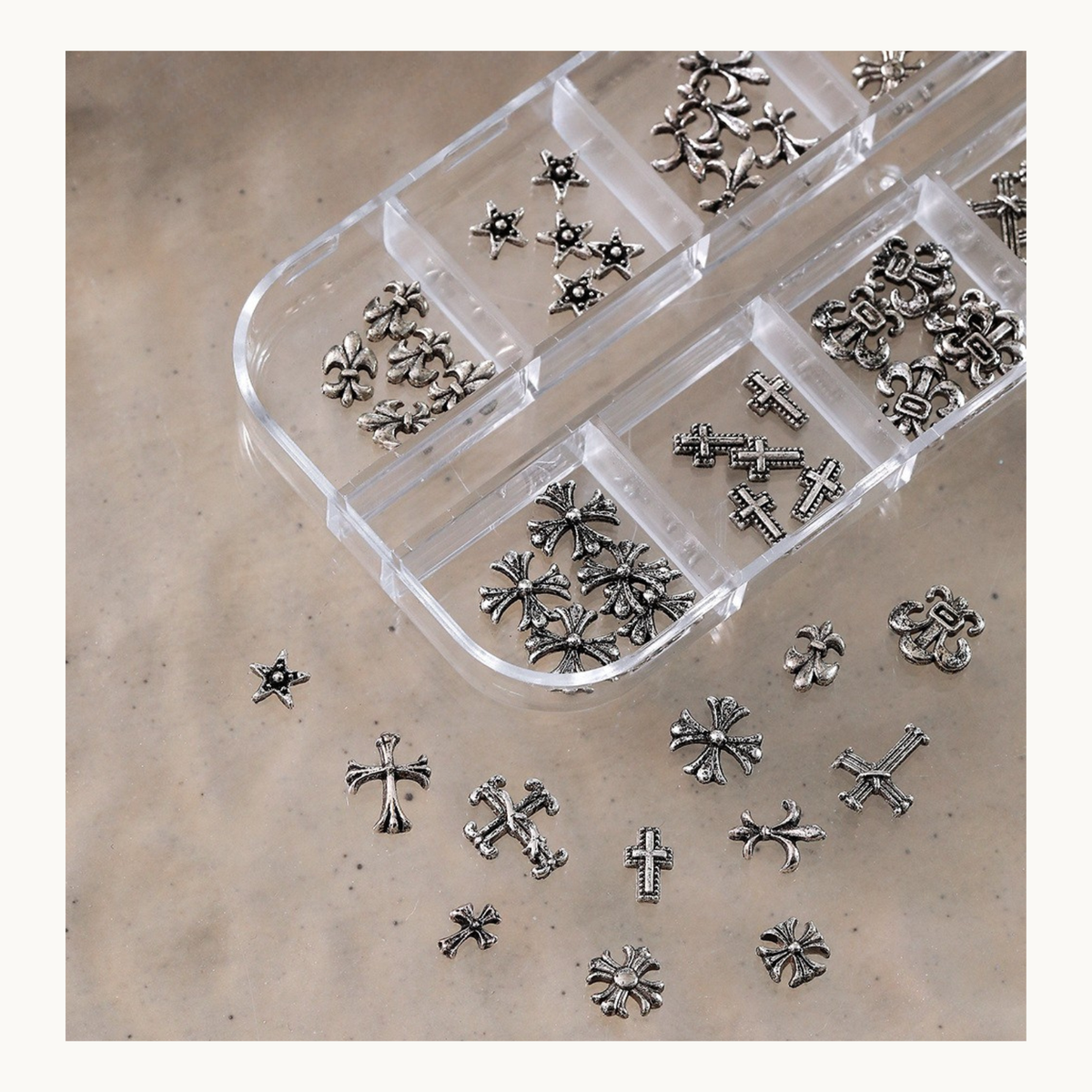 Close-up of silver gothic cross charms in a clear organizer with loose pieces