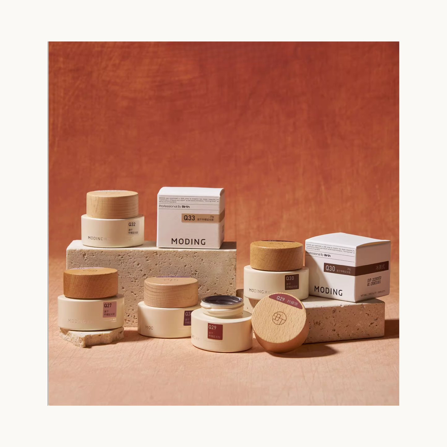 MODING builder gel jars and boxes displayed on stone blocks in a warm-toned studio setting.