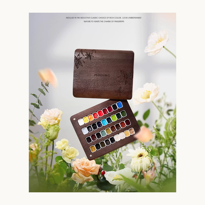 MODING 36-color solid watercolor palette displayed among blooming flowers, featuring wooden case and vibrant color pans.