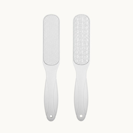 White dual-sided stainless steel foot file with an ergonomic handle for smoothing rough, hardened skin during pedicure care.