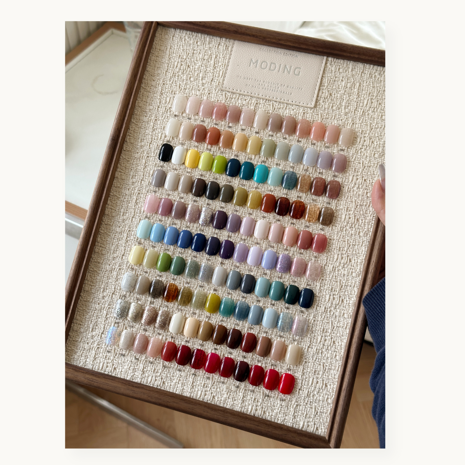 Close-up of MODING 130-color framed swatch board featuring full shade range including neutrals, brights, and glitters.