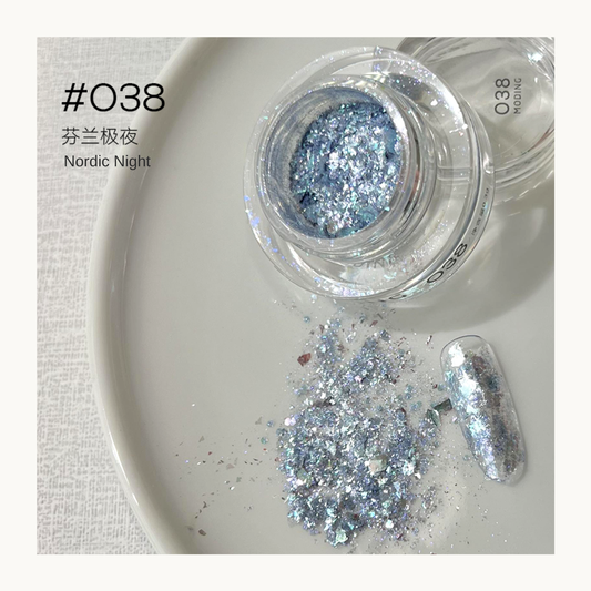 Blue-silver iridescent nail art flakes in a jar with a decorated nail swatch