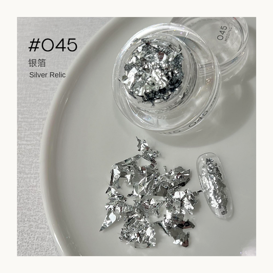 Silver reflective nail art flakes in a jar with a decorated nail swatch