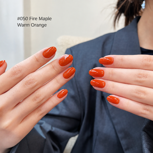Warm orange-red nail color gel manicure displayed on two hands