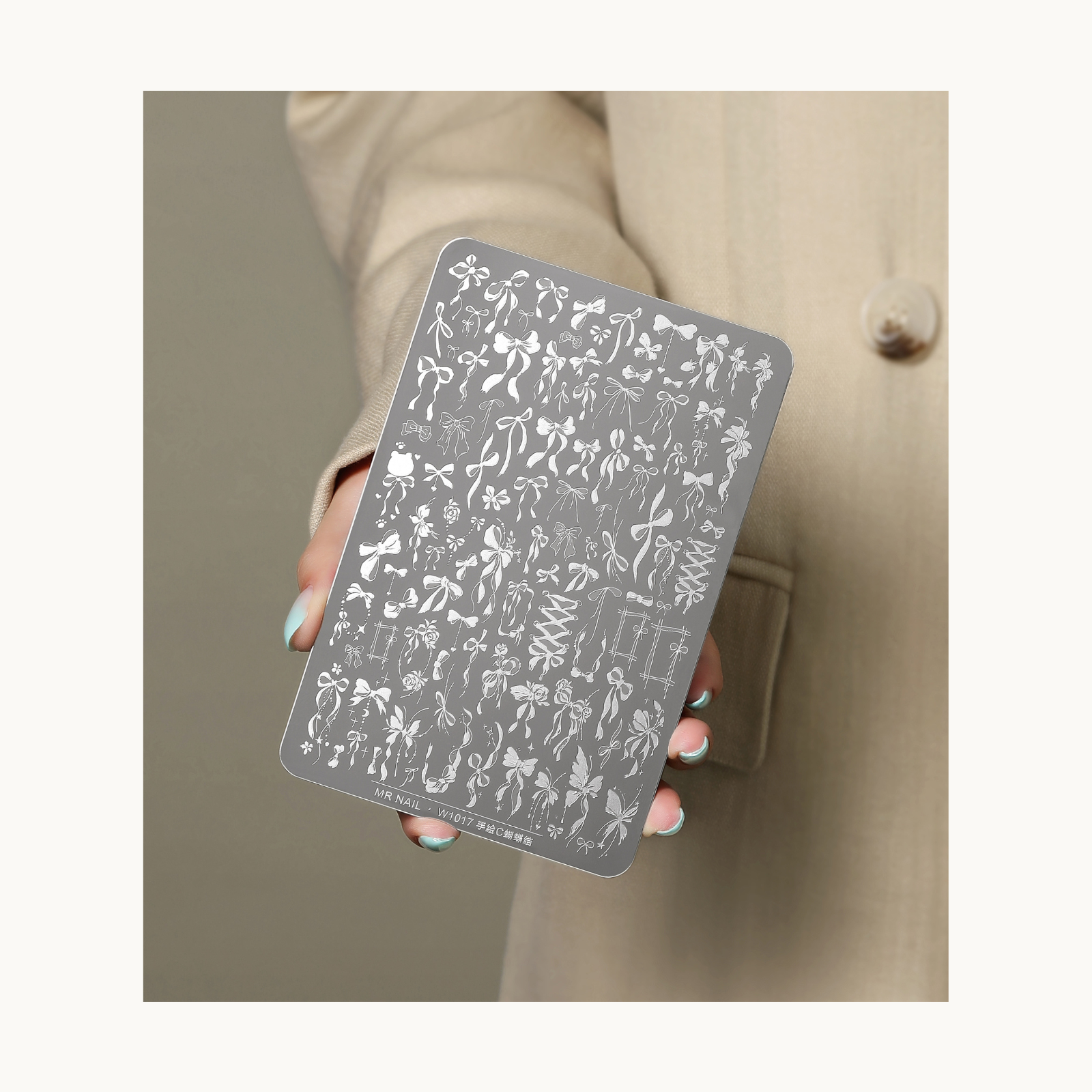 MR NAIL W1017 ribbon nail stamping plate held in hand, showing intricate bow patterns for nail art