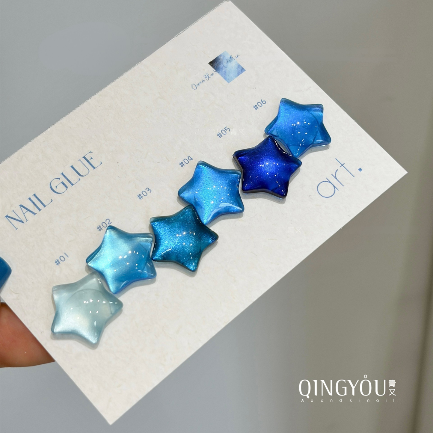 Six blue QINGYOU gel polish shades displayed on star-shaped swatches