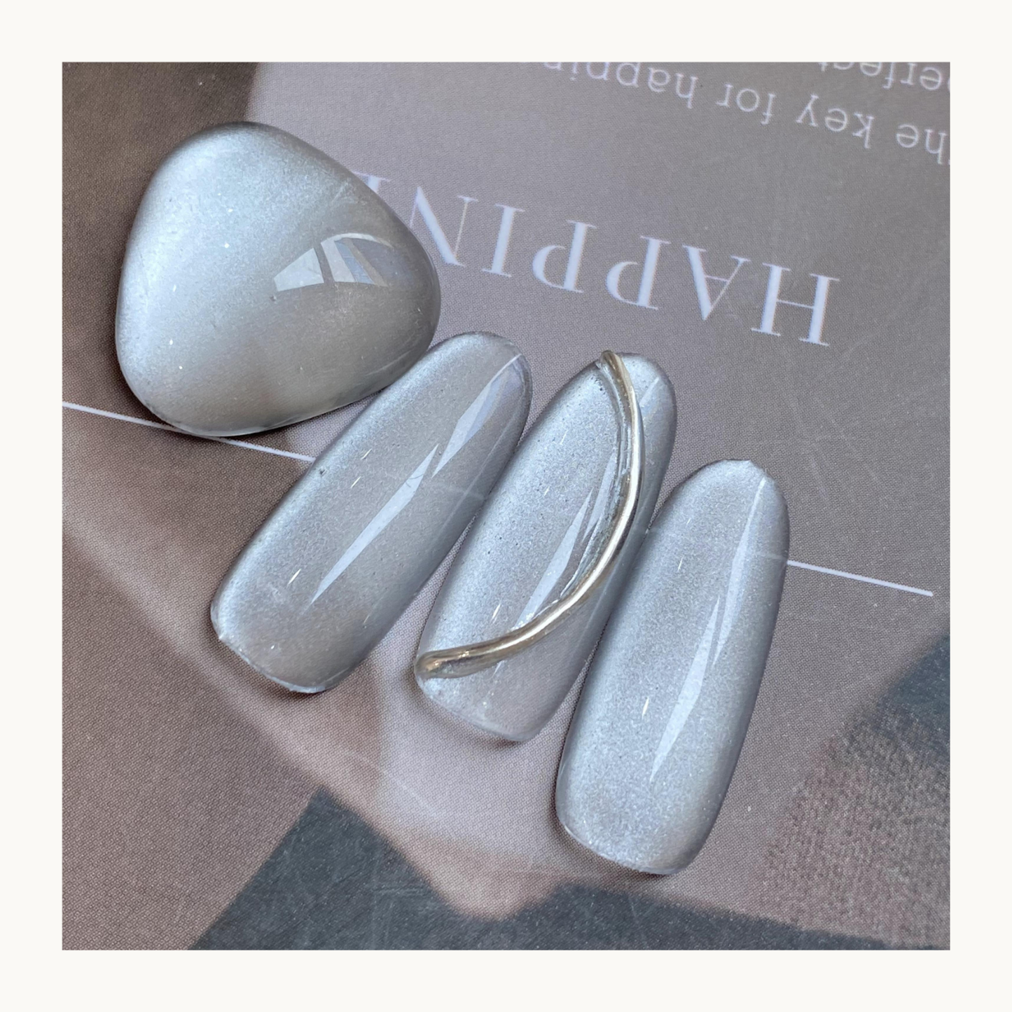 Qingyou Waterglow White Cat Eye Gel swatch showing smooth silver-white magnetic shine, flatlay nail art display.