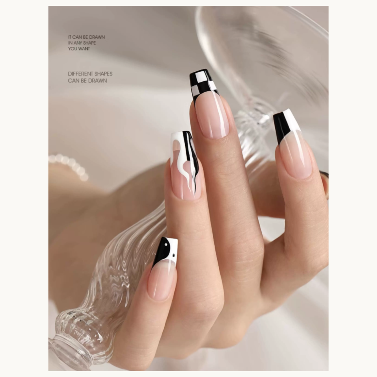 Black-and-white French and abstract nail art displayed on a hand