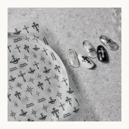 Tomoni celestial nail sticker sheet displayed with black, white and clear manicure designs featuring stars, planets and crosses.