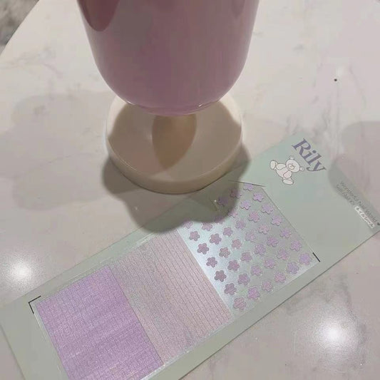 Lavender flower nail sticker card with pink panels beside a purple glass