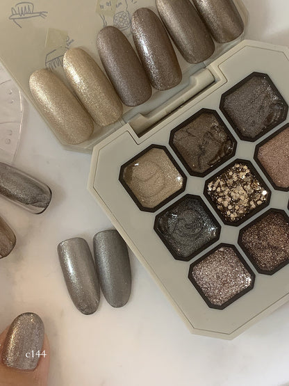 Close-up of silver-gray shimmer gel on a fingernail beside the palette