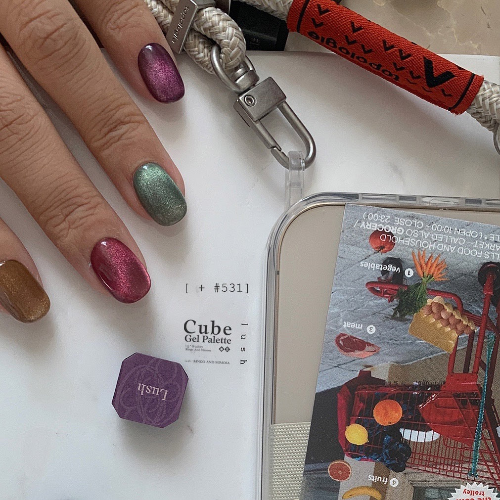Multicolor soft gel manicure beside a smartphone and braided lanyard