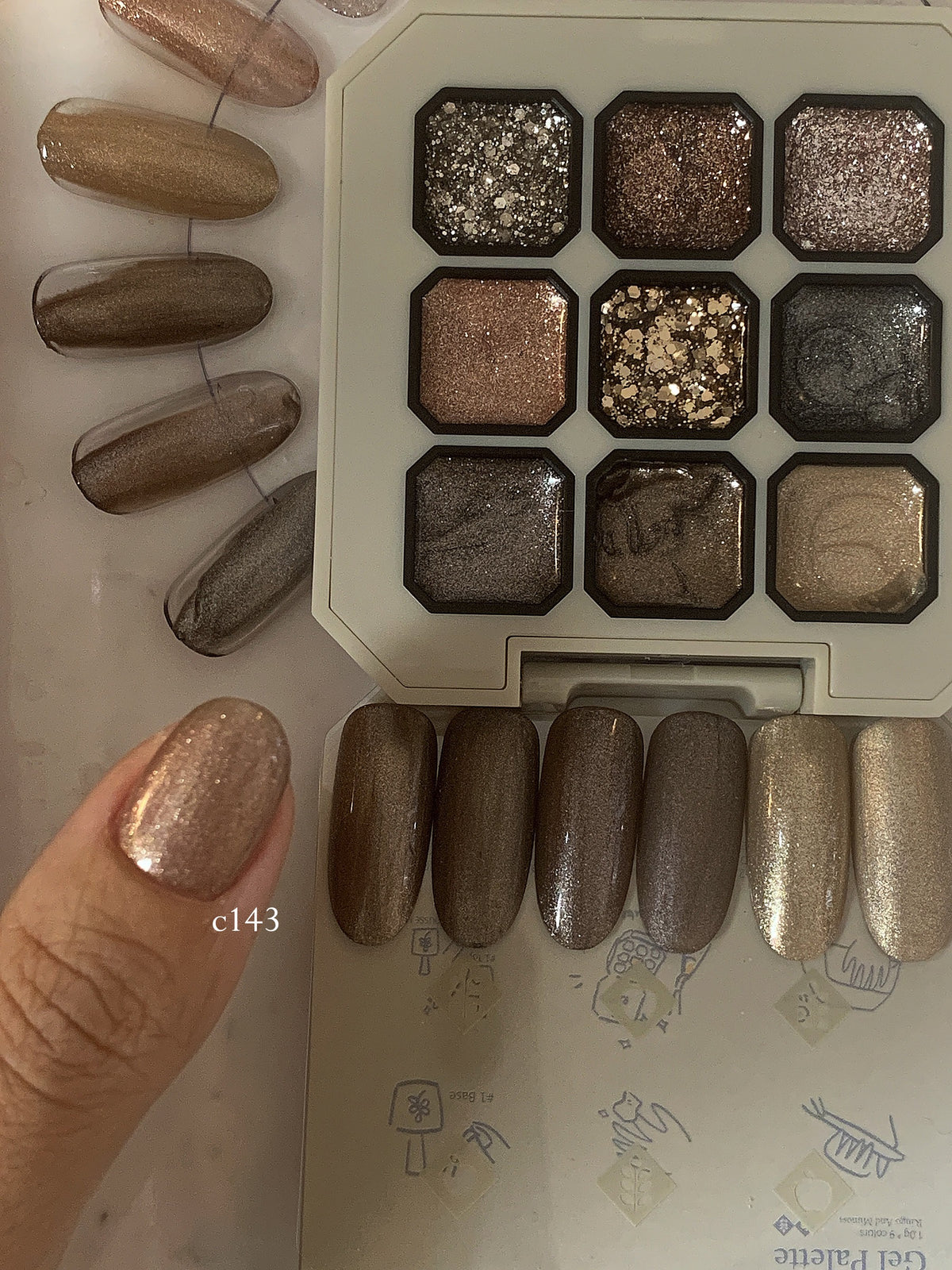 Close-up of rose-gold shimmer gel on a fingernail beside the palette