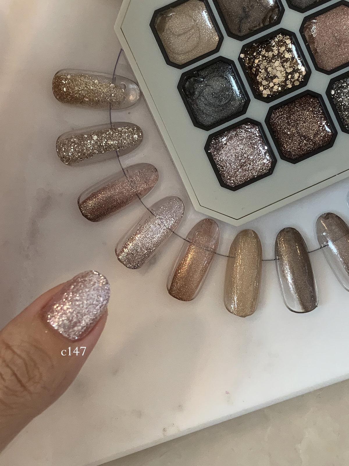 Close-up of silver glitter gel on a fingernail beside the palette