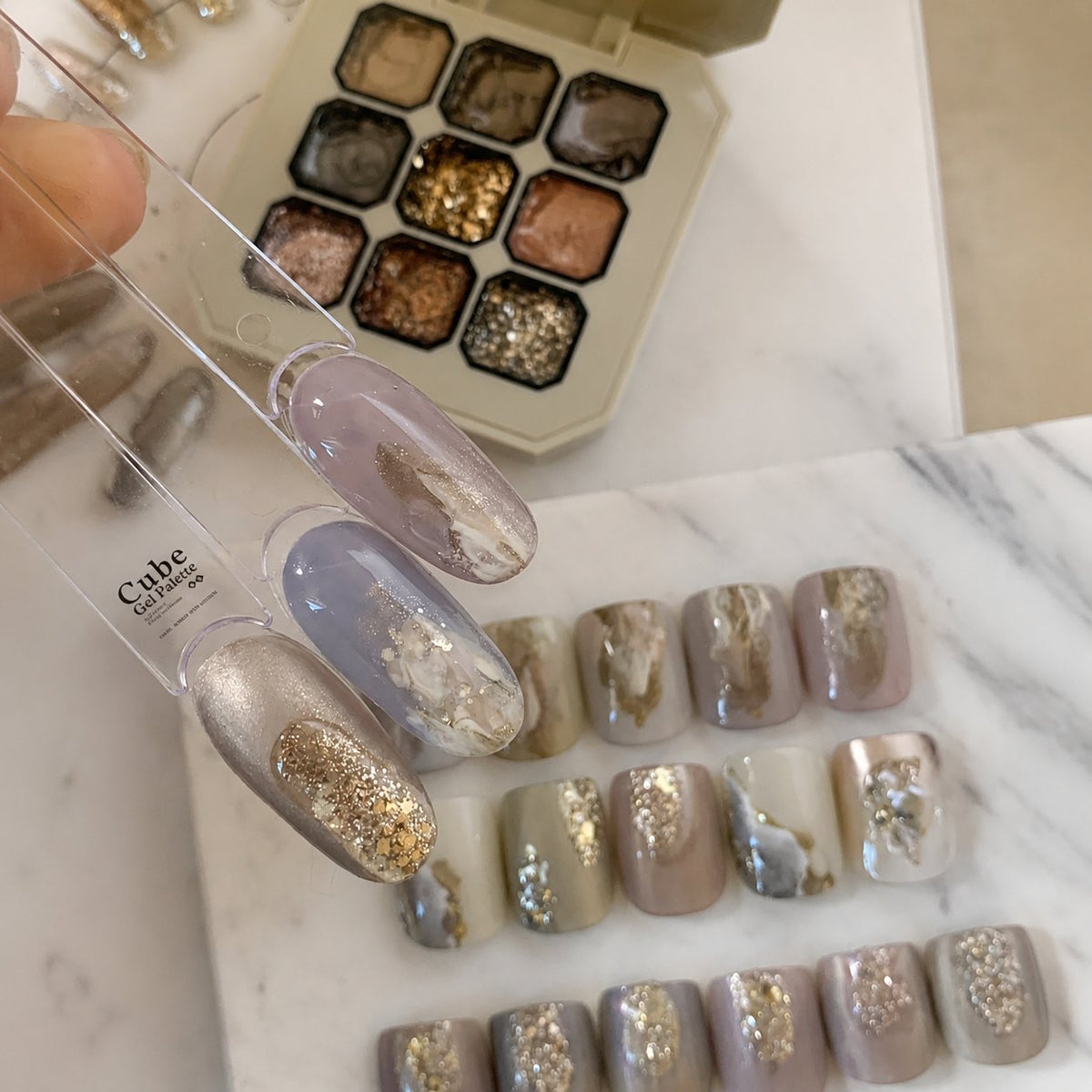Close-up of mauve and glitter gel nail tips over the palette