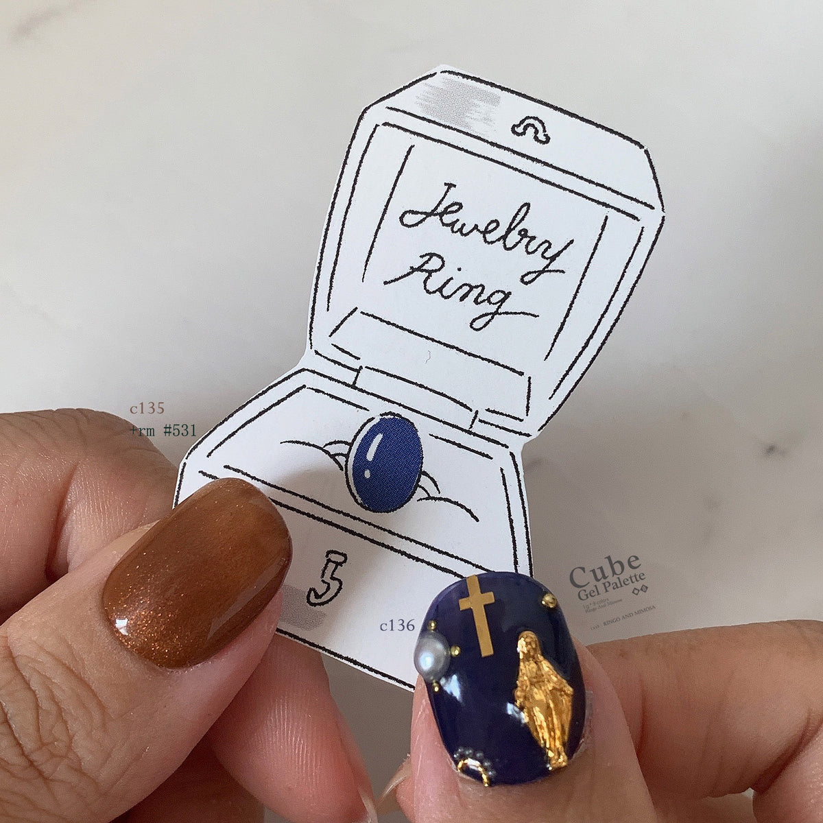 Close-up of brown and navy soft gel manicure with gold embellishments