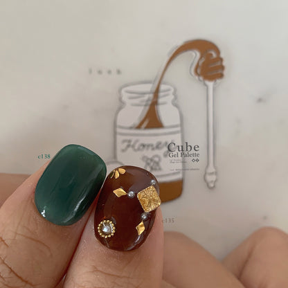 Close-up of teal and brown soft gel manicure with gold square charm