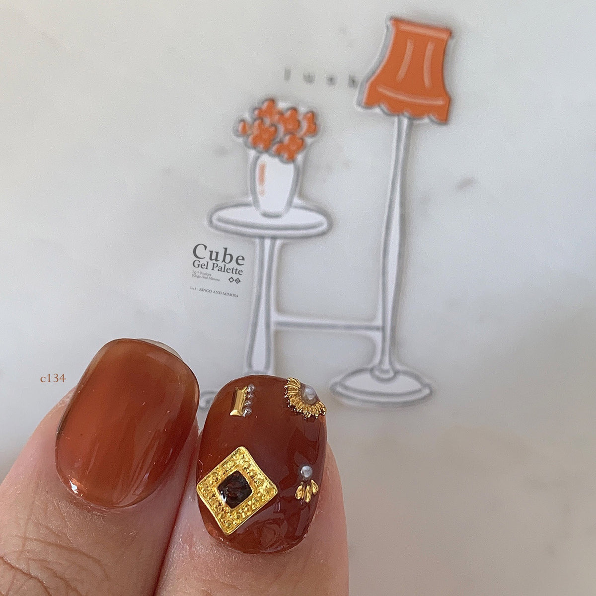 Close-up of orange-brown soft gel manicure with gold square charm